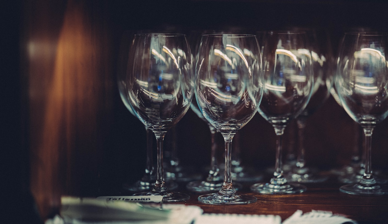 Two empty wine glasses on a wooden table — one taller and narrower, one wider and balloon-shaped