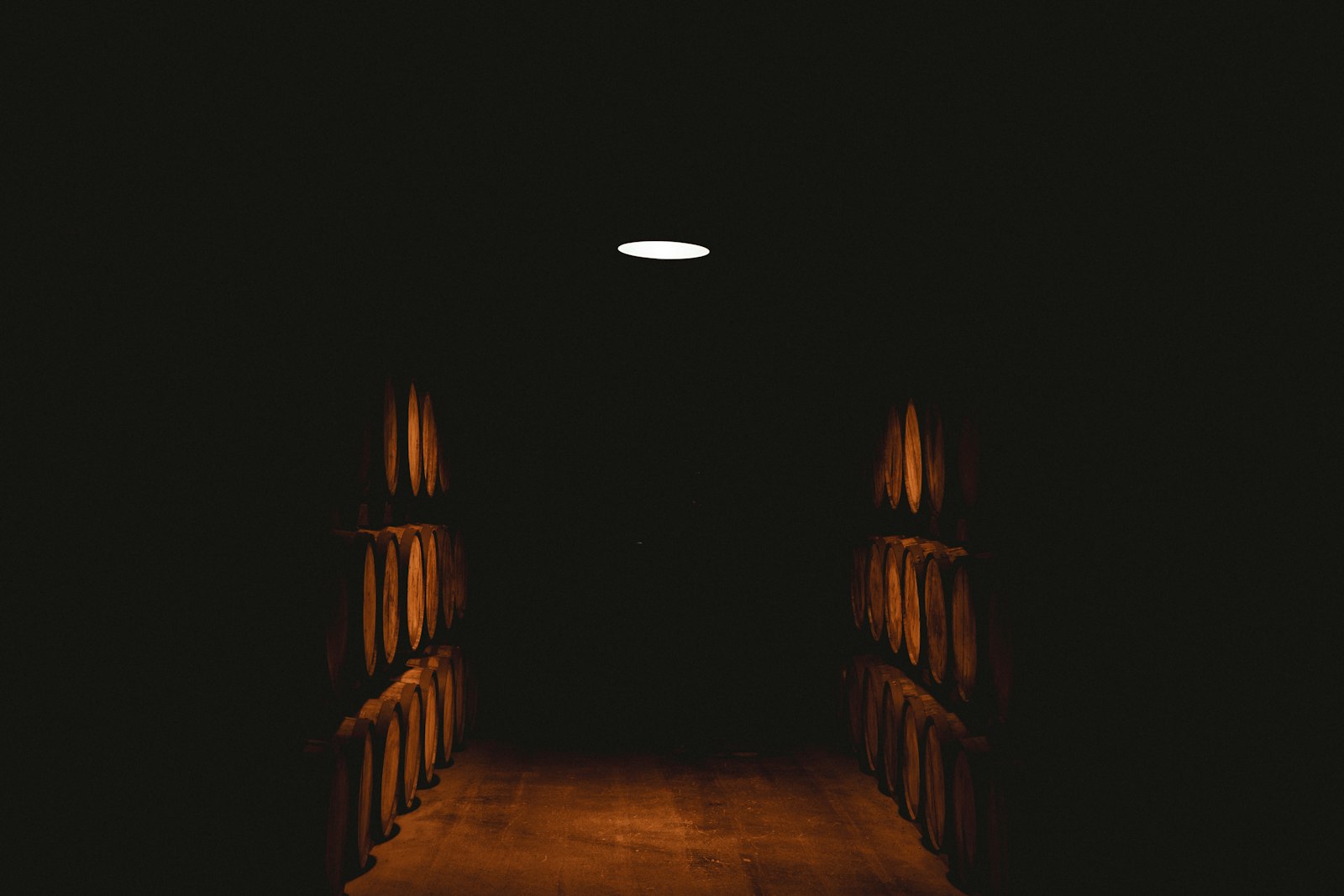 Warm-lit dim cellar atmosphere conveying the heat and transformation of barrel toasting