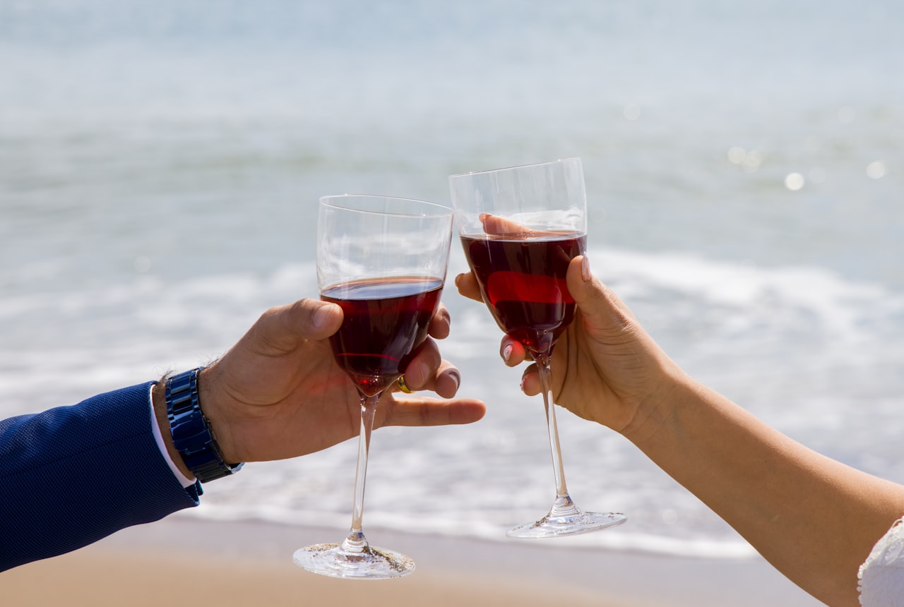 A hand holding a wine glass against a soft white tablecloth, slightly tilted