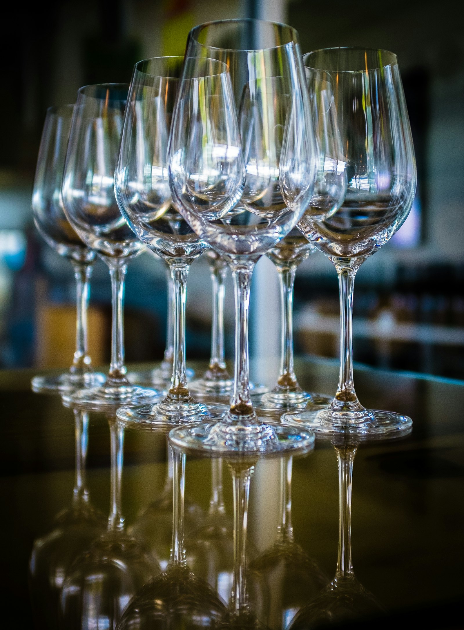 A row of empty wine glasses on a dark wood table